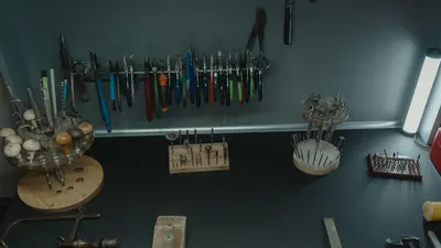 Établi de bijoutier professionnel avec une variété d'outils de précision rangés sur des supports et au mur.
