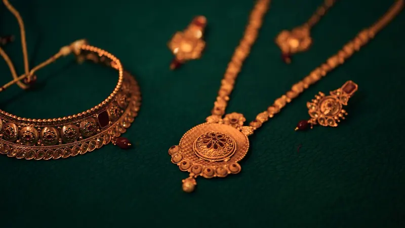 Ensemble de bijoux indiens traditionnels en or avec des pierres rouges posés sur un fond vert foncé.